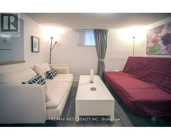 A living room with a white couch and a red bed.