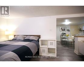 A bedroom with a bed and a small table with chairs in the other room.