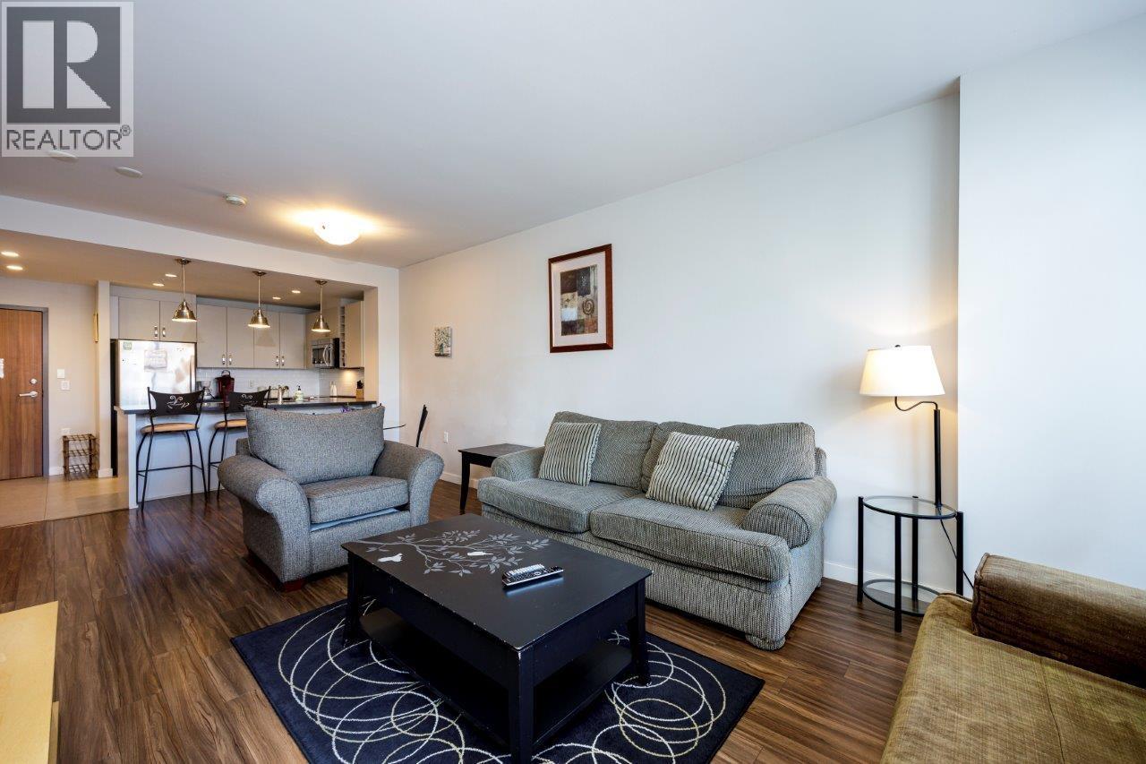 A living room with a grey couch, a coffee table, and a lamp.