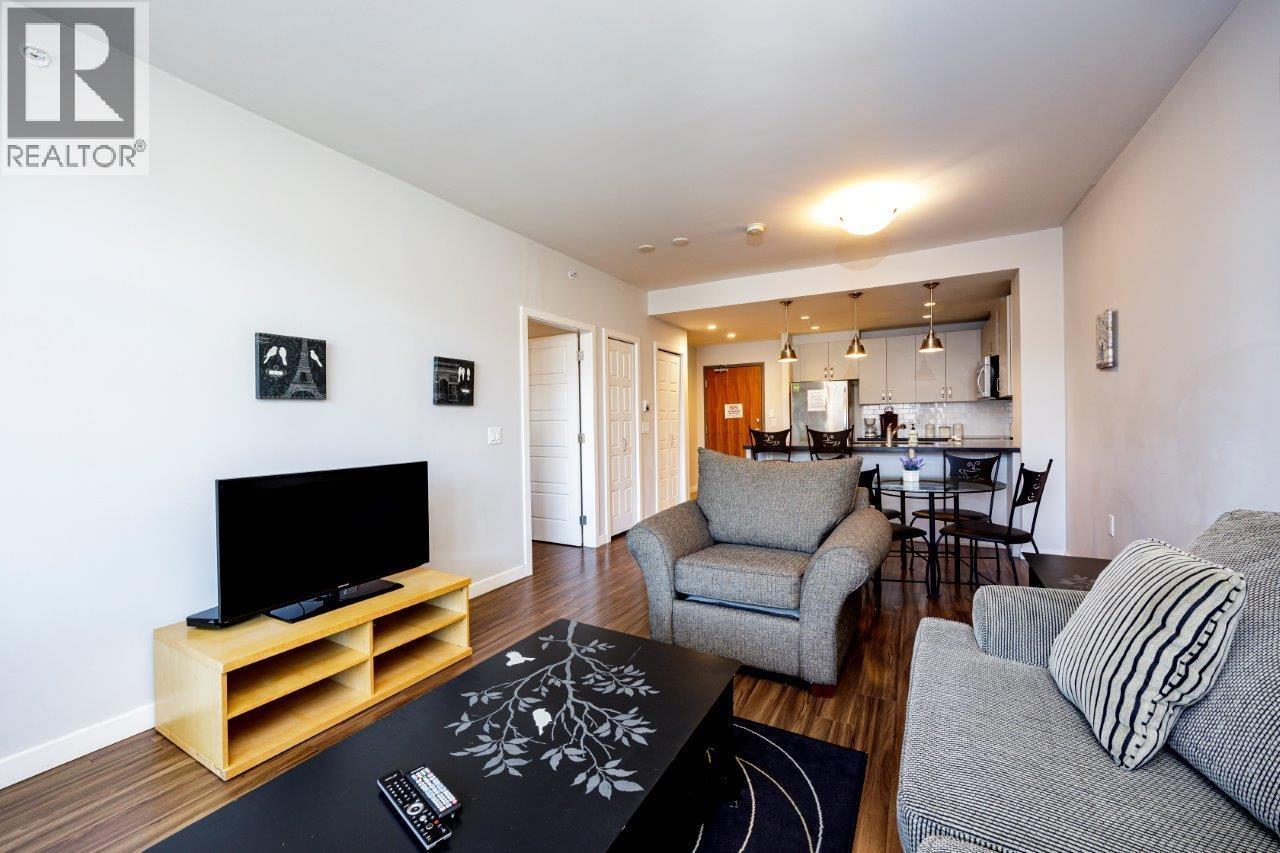 A living room with a grey couch and a wooden tv stand.