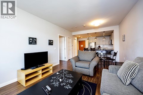 A living room with a grey couch and a wooden tv stand.