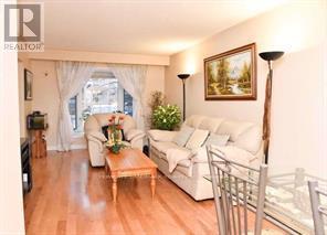 A living room with a white couch, a wooden coffee table, and a painting on the wall.