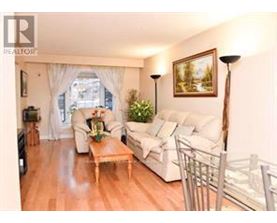 A living room with a white couch, a wooden coffee table, and a painting on the wall.