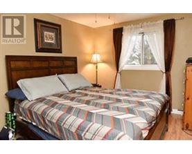 A bedroom with a bed, a lamp, and a window with curtains.