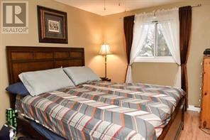 A bedroom with a bed, a lamp, and a window with curtains.