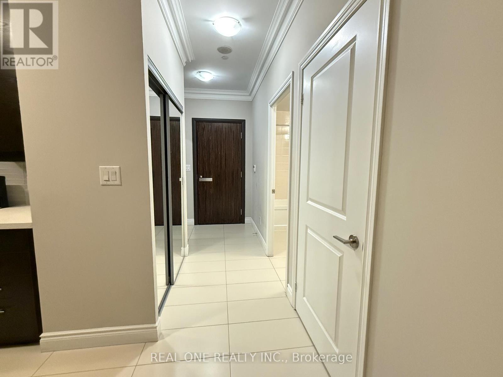 A hallway with white walls and a brown door.