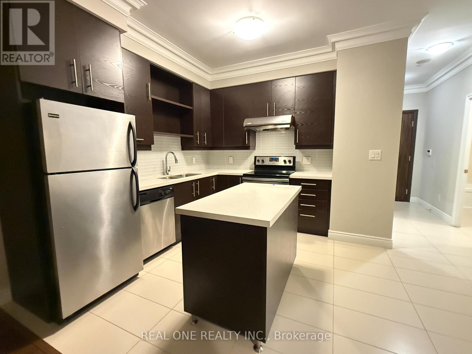 A modern kitchen with dark brown cabinets and stainless steel appliances.