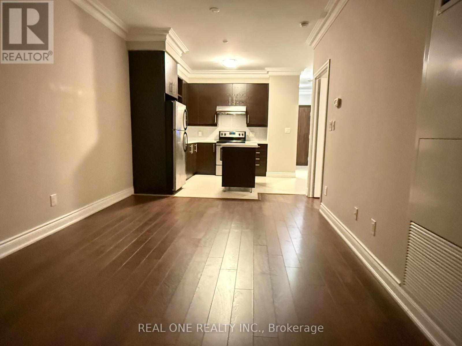 A spacious kitchen with dark wood floors and white walls.