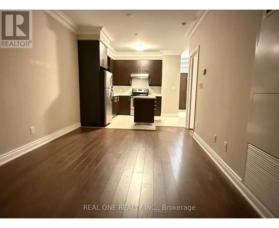 A spacious kitchen with dark wood floors and white walls.