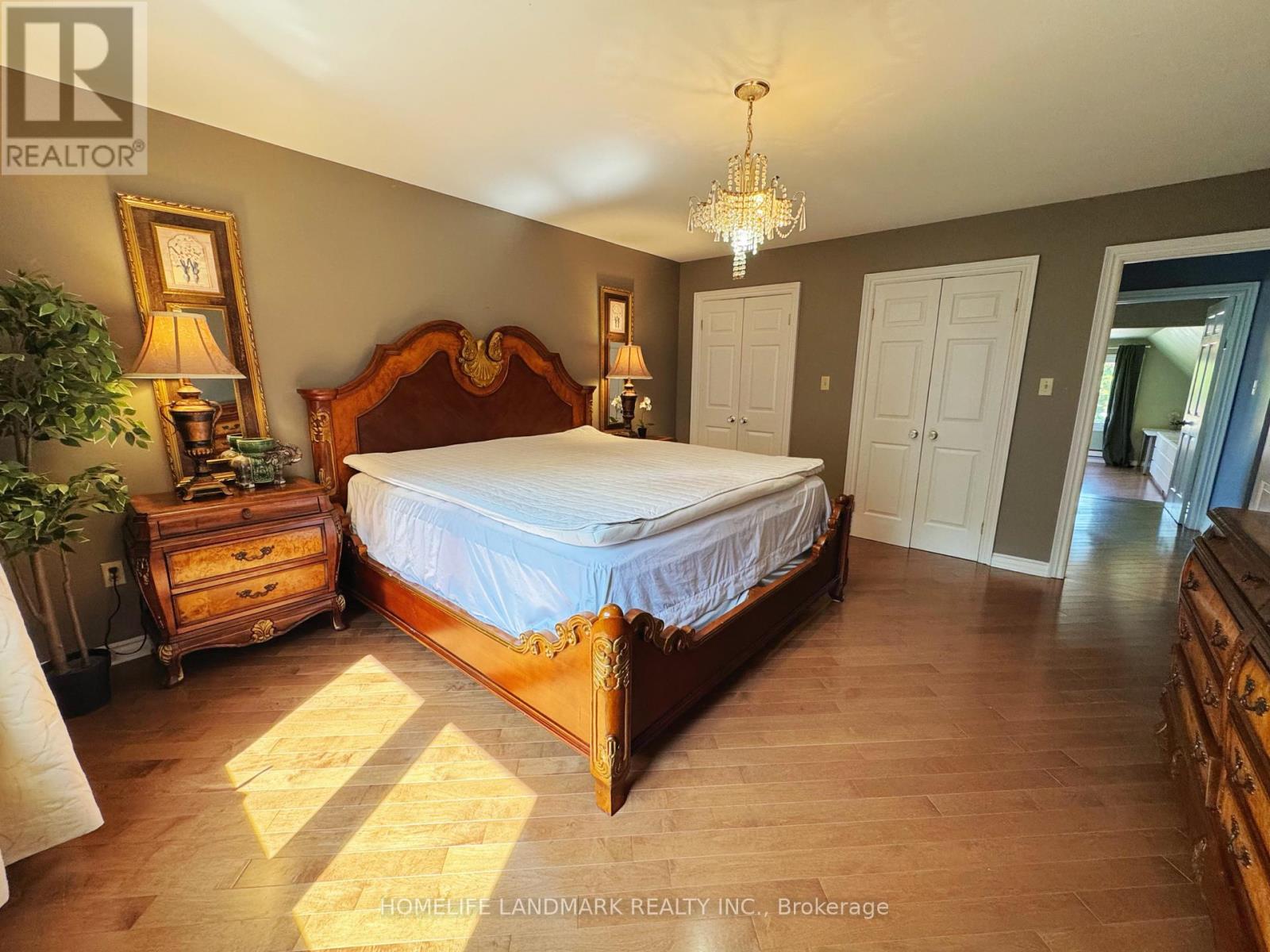 A bedroom with a large bed, a chandelier, and a dresser.