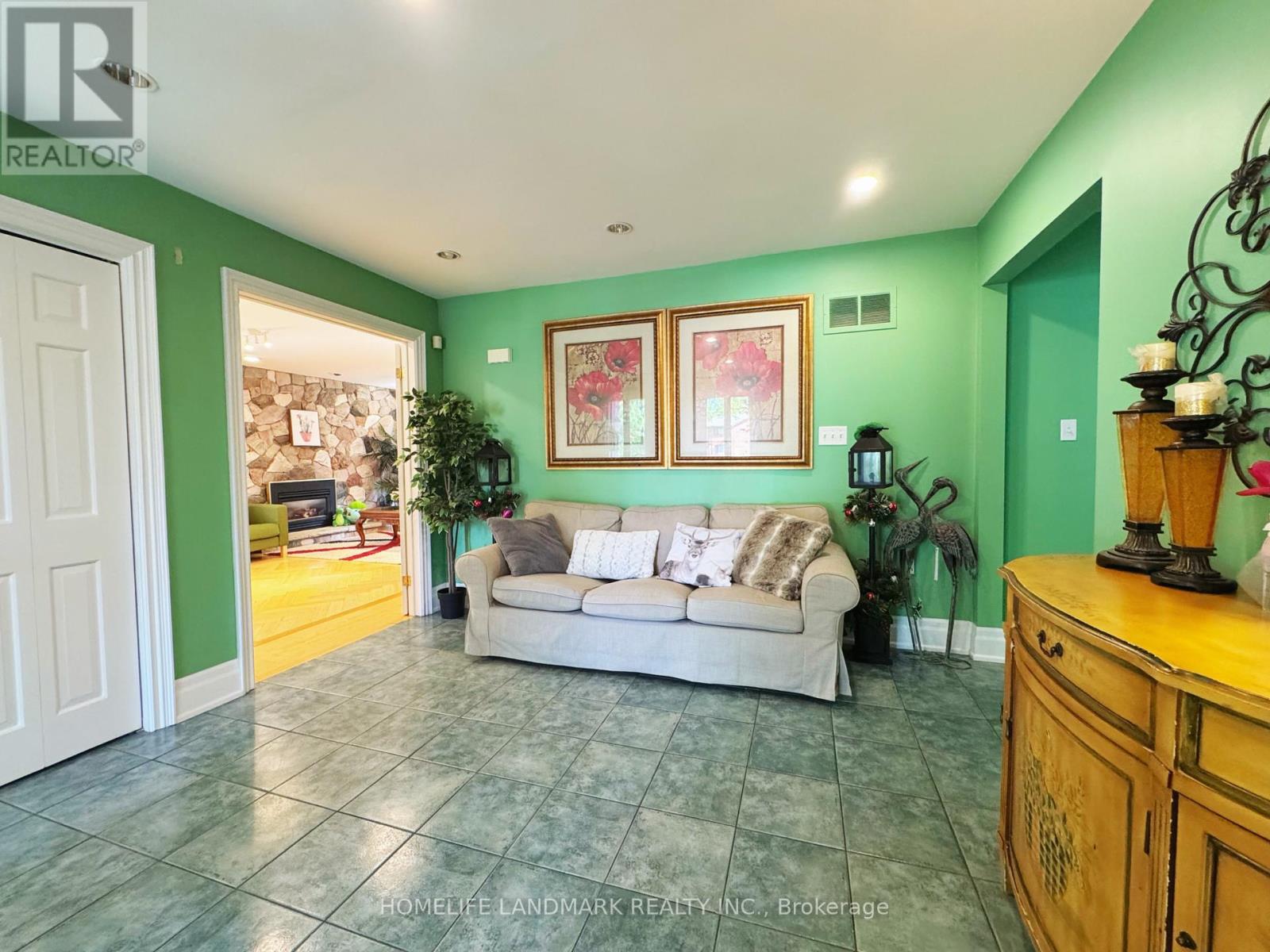 A living room with a couch, a plant, and a painting on the wall.