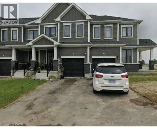 A white car is parked in front of a grey house.