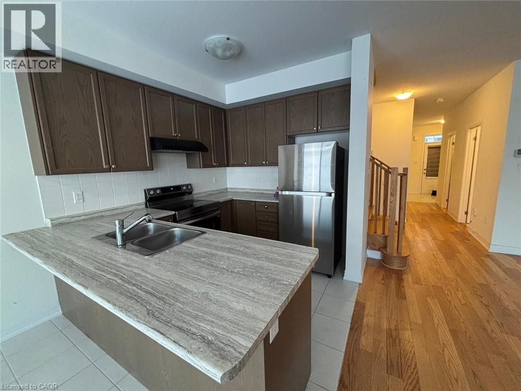 A kitchen with a refrigerator, sink, and stove.