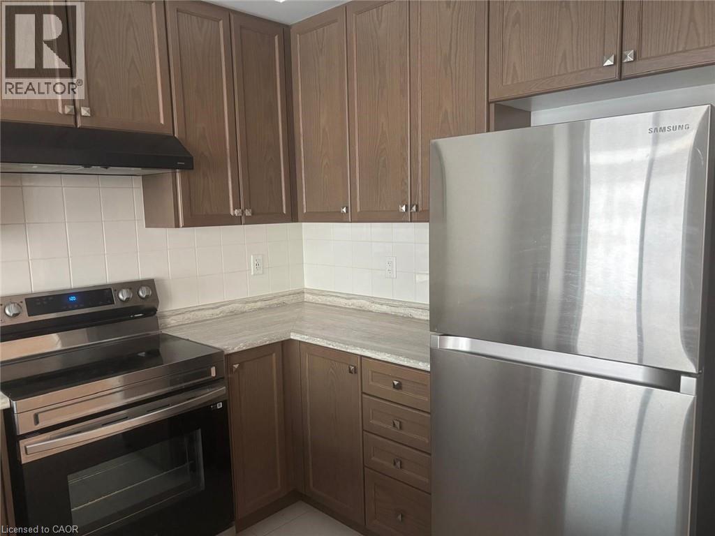 A kitchen with a stainless steel refrigerator, black stove, and wooden cabinets.