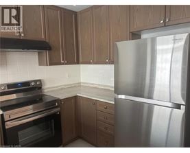 A kitchen with a stainless steel refrigerator, black stove, and wooden cabinets.