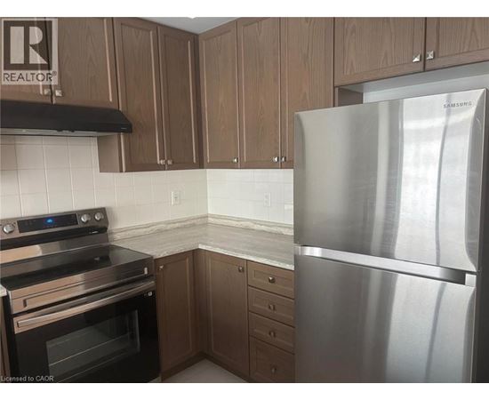 A kitchen with a stainless steel refrigerator, black stove, and wooden cabinets.