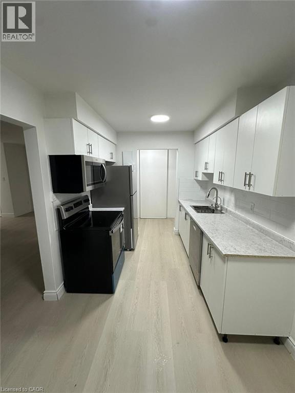 A kitchen with white cabinets and a grey counter top.