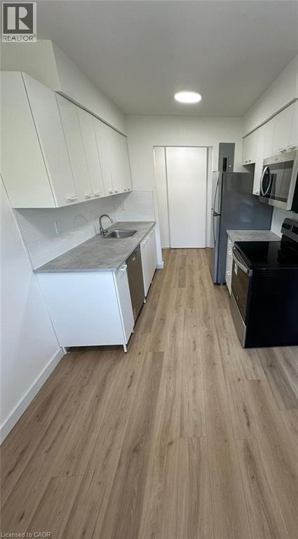 A kitchen with white cabinets and a wooden floor.