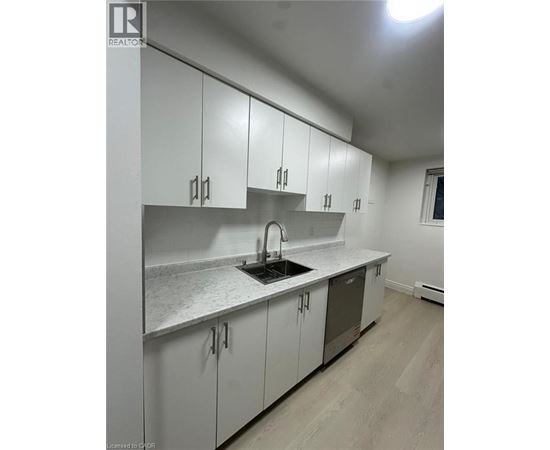 A kitchen with white cabinets and a wooden floor.