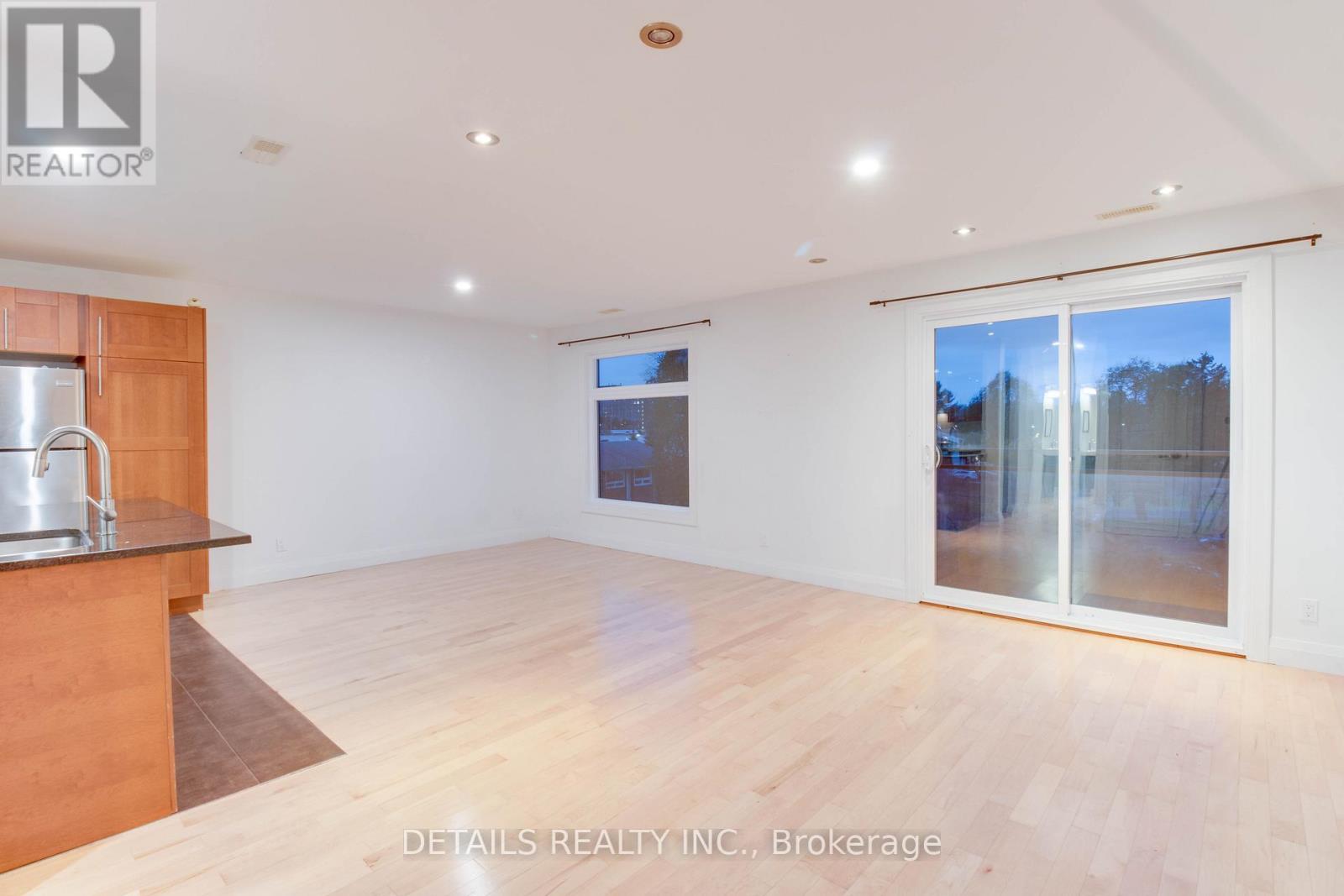 A spacious room with a wooden cabinet and a glass door leading to a balcony.