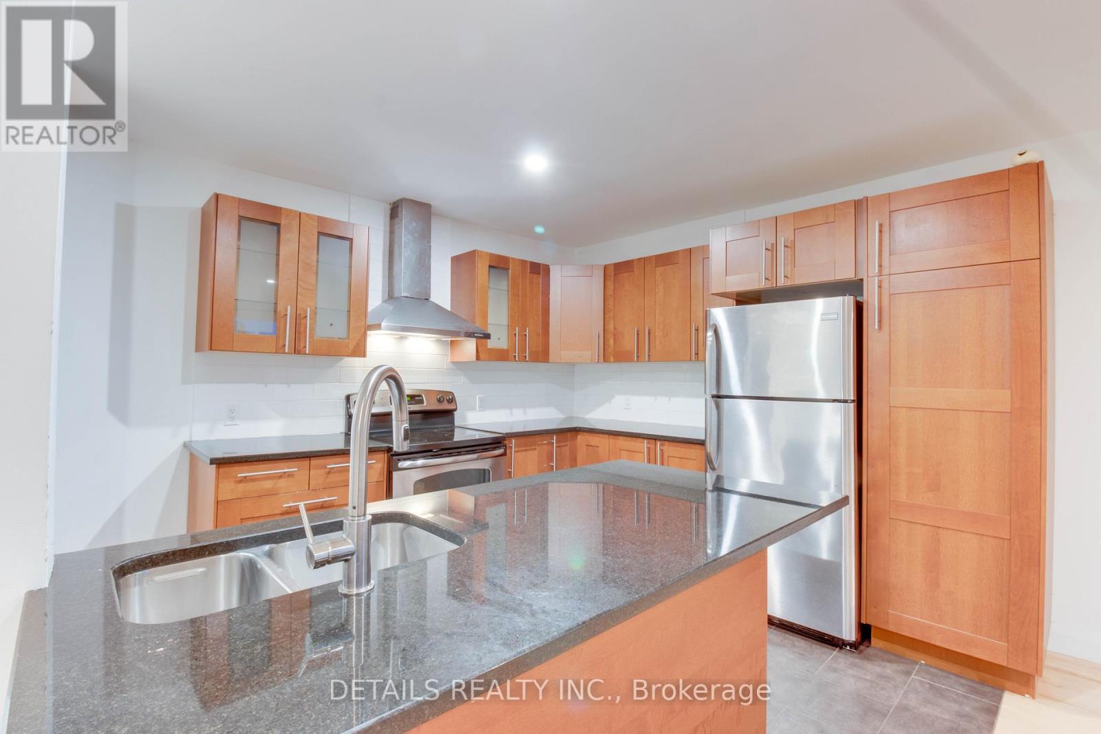 A kitchen with wooden cabinets and a stainless steel refrigerator.