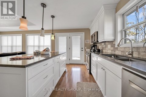 A kitchen with white cabinets and a wooden floor.