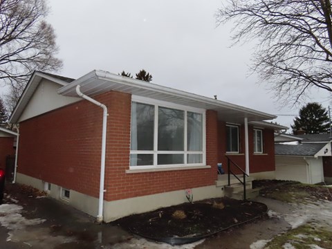 A red brick house with a white roof and a small front yard.