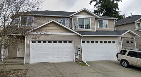A two-story house with a garage and a car parked in front.