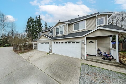 A house with a garage and a bicycle parked in front.