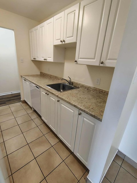 A kitchen with white cabinets and a granite countertop.