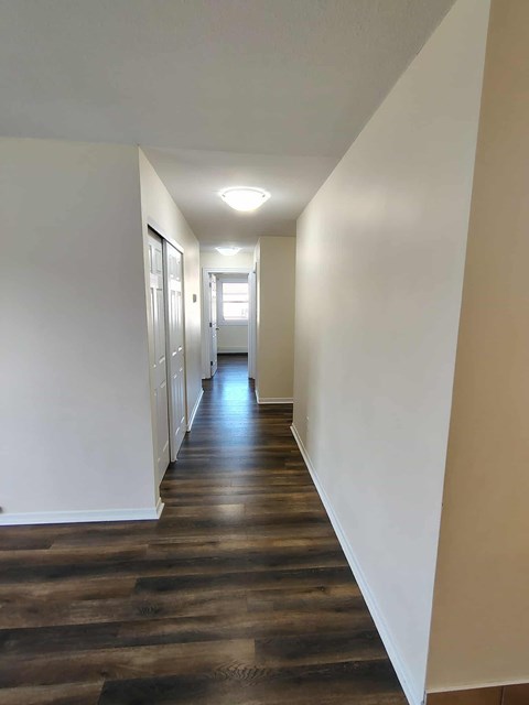 A long hallway with wood floors and white walls.