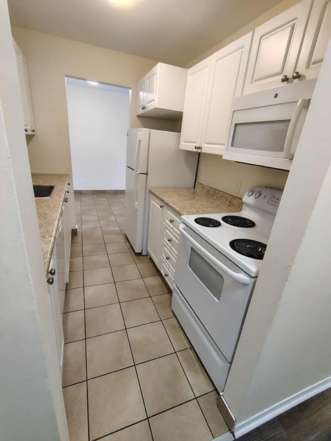 A kitchen with white appliances and cabinets.