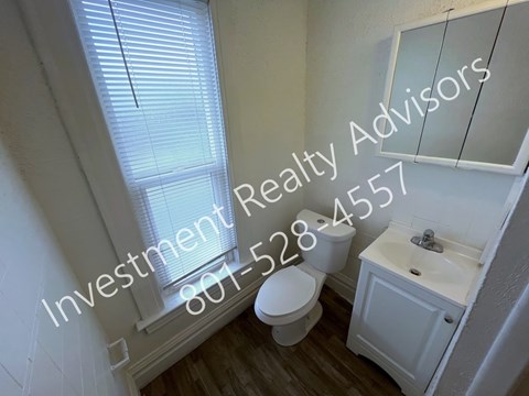 A white bathroom with a toilet, sink and mirror.