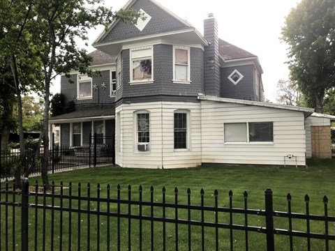 A white house with a black fence in front.