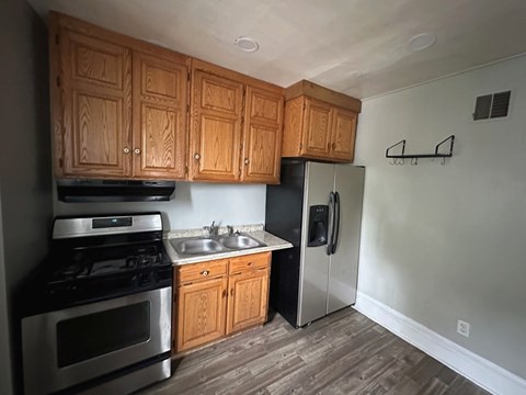 A kitchen with wooden cabinets and a stainless steel refrigerator.