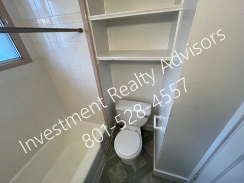 A white toilet is in a bathroom with a white cabinet and a window.