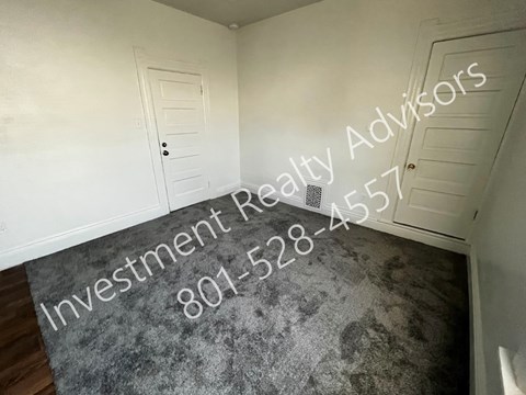 A hallway with a rug on the floor and a door on the left side.