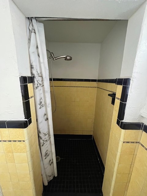 A bathroom with yellow tiles and a black and white shower curtain.