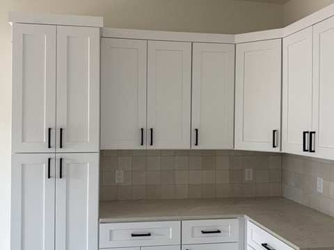 A kitchen with white cabinets and drawers.