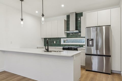 A modern kitchen with a stainless steel refrigerator and white cabinets.
