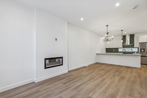 A spacious room with wooden flooring and a fireplace.