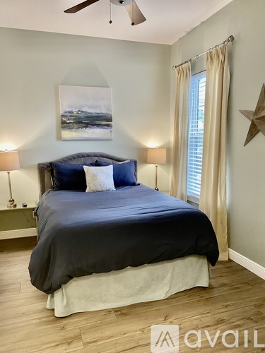 A bedroom with a large bed and a painting on the wall.