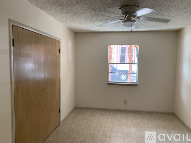 A room with a ceiling fan and a door leading to another room.