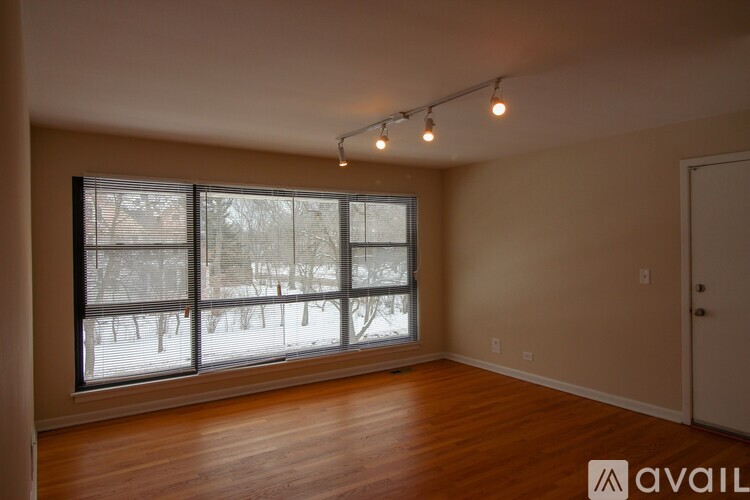 A room with wooden floors and a large window overlooking a snowy landscape.