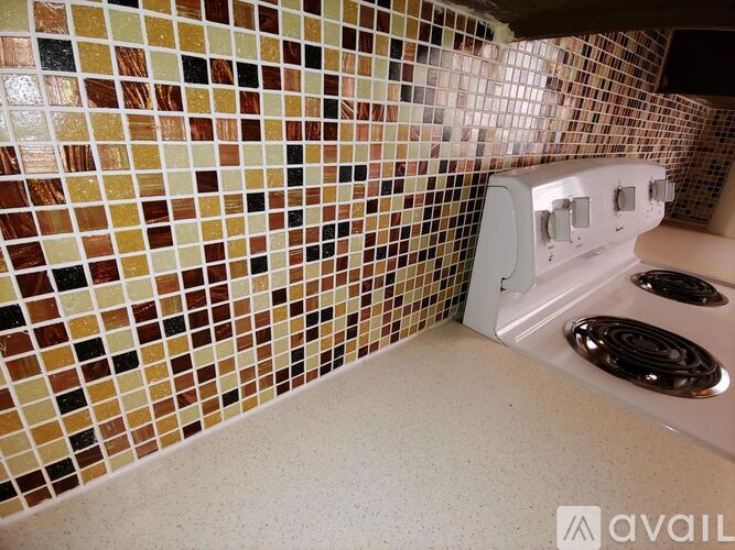 A kitchen with a stove and tiled walls.
