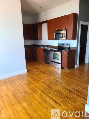 A kitchen with wooden floors and brown cabinets.