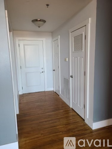 A hallway with wood floors and white doors.
