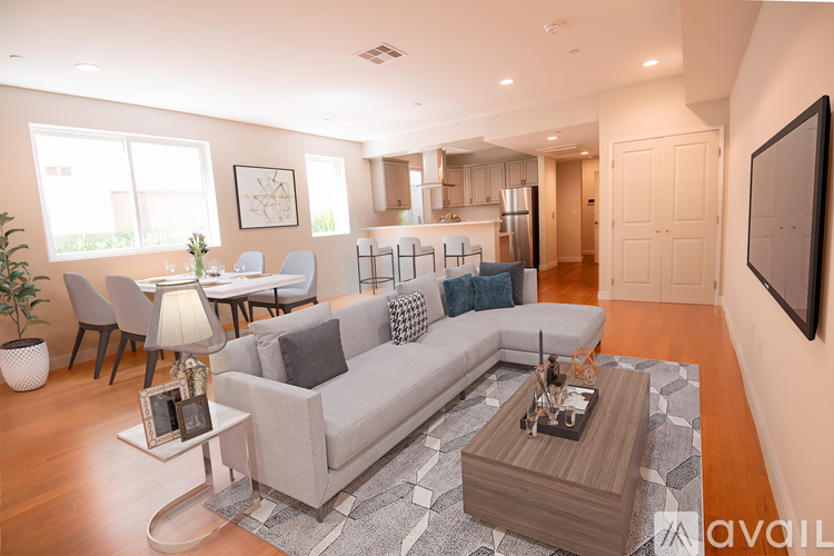 A modern living room with a grey sofa, a coffee table, and a flat-screen TV mounted on the wall.