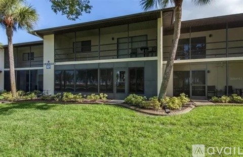 A building with a lawn in front and a tree to the left.