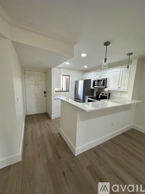 A kitchen with white cabinets and a wooden floor.